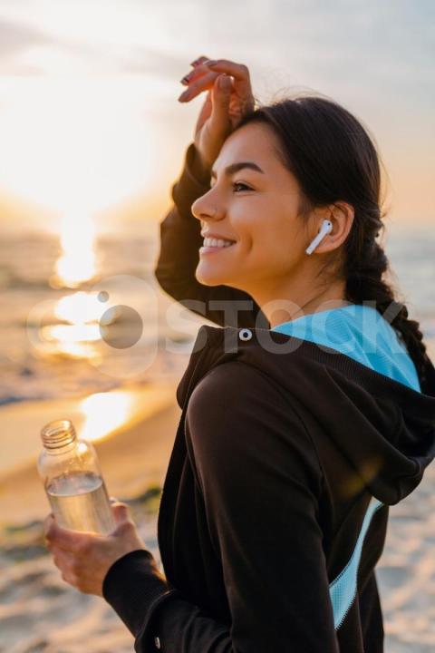 Attractive slim woman doing sport exercises morning sunrise beach sports wear thirsty drinking water bottle healthy lifestyle listening music wireless earphones hot summer day 285396 5566 jpg 1
