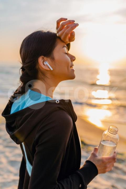 Attractive slim woman doing sport exercises morning sunrise beach sports wear thirsty drinking water bottle healthy lifestyle listening music wireless earphones smiling happy 285396 5567 jpg